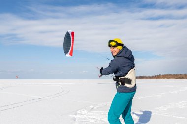 Birçok insanın panoramik görüntüsü, dondurucu göl karlı yüzeyinde açık güneşli bir kış gününde sıcak bir takım elbiseyle uçurtma sörf tahtası sürmekten keyif alır. Kış sporu adrenalin eğlence macera hobisi keskinlik.