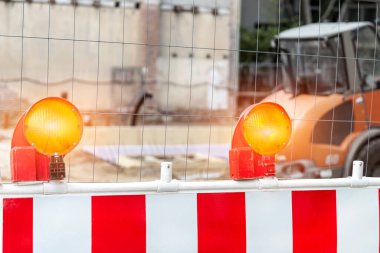 Kapalı çekim portakal rengi yanıp sönen ışık bariyerini çit inşaat alanının önünde görebilirsiniz. Güvenlik ekipmanları sigorta lambası şehir binası inşaat makineleri trafiği.