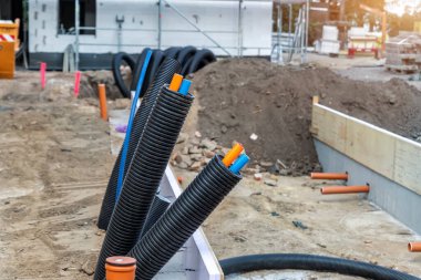 Siyah PVC kıvrımlı plastik yalıtım boruları elektrik kablolarının kablo boruları dezenfekte edilmemiş tesiste. Mühendislik boru hattı drenaj teknolojisi olan yeni modern inşaat alanı.