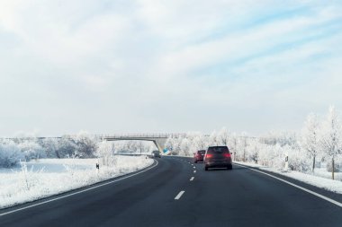 Manzarası temiz şehirlerarası otoban araçları güzel beyaz kar ağaçları ile arka planda mavi gökyüzü açık, güneşli bir günde. Kentsel soğuk kar günü kar fırtınası arka planı.