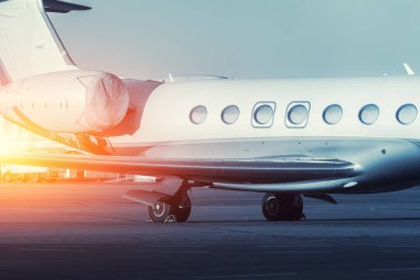 Scenic side close view modern luxury expensive private jet plane parked airport taxiway hangar warm colorful dramatic evening sunset sun light sky background. Executive aicraft vip travel concept.