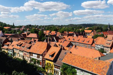 Scenic panoramic view traditional shingle tiled red rooftop old ancient medieval european german small town Quedlinburg church against blue sky background. Unesco heritage list travel destination.