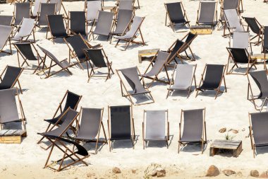 Scenic water view of many empty black wooden deckchair loungers on sand river or sea ocean beach. Rows of deckchair on closed coast due contamination. Lack of people tourist on resort due sanctions.