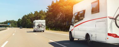 Scenic view big modern white family rv camper van vehicle driving on european highway road against blue sky in summer day. Rving motorhome lifestyle travel and adventure tourism trip journey concept.