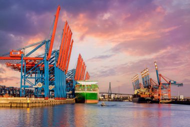 Sahne önü dev kargo konteynır gemisi Hamburg liman limanı vinçlerini dolduruyor sıcak dramatik akşam gün batımı. Küresel ticari taşımacılık kiralama sözleşmesi lojistik geçmişi.
