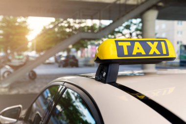 Otomobillerin üstündeki sarı taksi sembolü havaalanı terminalinin otoparkında ya da tren istasyonunda park sıcak akşamları Bokeh güneş ışığına karşı bekliyor. Kentsel sokak ulaşım konfor hizmeti.