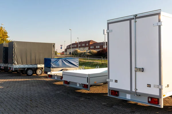 Many different types small passenger car cargo freight trailers parked in row at sale or rental site. Business and home transportation delivery. Service production and maintenance equipment.
