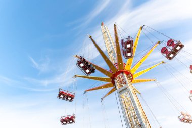 Manzaralı alt manzara yüksek zincirli salıncak mavi gökyüzüne doğru uçan atlıkarınca. Merry, portatif lunaparktaki şöförlü uçağın etrafından dolaş. İnsanlar panayır festivalinde aile eğlencesine binmekten hoşlanıyor..