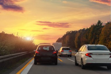 Otoyol trafiğinde sıkışan birçok aracın arka kuyruk görüntüsü sıcak gün batımı saatine denk geliyor. Trafik kazası, trafik kazası. Şehir taşımacılığı altyapı engelleme grevini durdurdu.