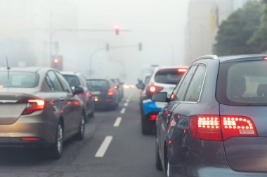 Manzaralı şehir trafiği trafik sıkışıklığı sisli, yağmurlu, sisli, sisli sabah, düşük görüş mesafesi soğuk bahar mevsiminde birçok arabayı cezbeder. Mevsimsel kötü yağmurlu hava kazası tehlike uyarısı araba sisi uyarısı.