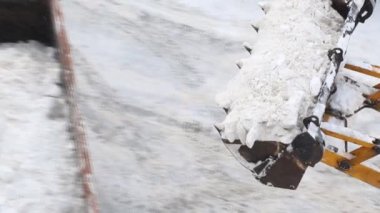 Kar küreme makinesinin kar küreme küreme küreklerinin kar ve buz yığınlarını kar fırtınasında şehir caddesinden kaldırmak için çöp kamyonuna yüklediği yakın plan görüntüsü. Kar temizleme ve kaldırma.