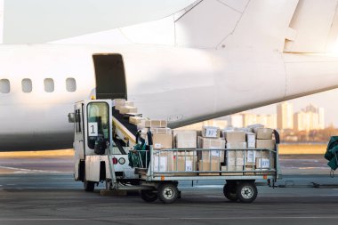 Turboprop kargo uçağına karşı ticari paketlerle dolu kargo vagonunun yakın çekim görüntüsü. Hava postası ve lojistik. Dışarıya aktarma işlemleri. Ticari charter uçuş servisi.