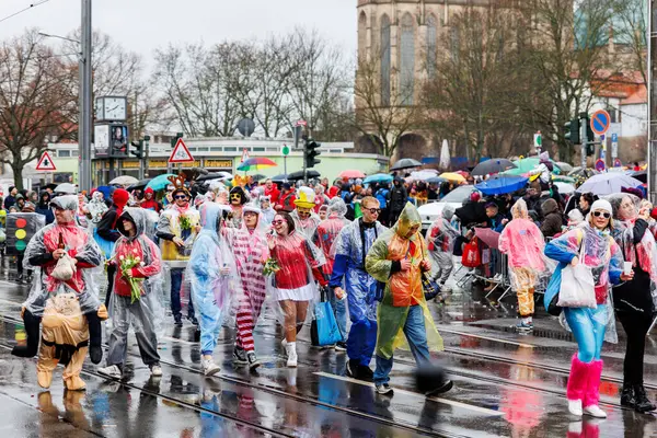 Erfurt, Almanya - 11 Şubat 2024: Geleneksel Alman Karnavalı Fasching 2024, Thüringen. İnsanlar şehir sokaklarında festival dansını kutluyor. Şiddetli yağmur altında yüzen şehir merkezinde eğleniyorlar..