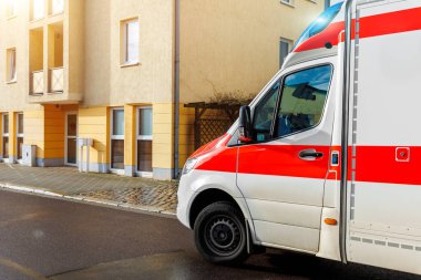 Yağmurdan sonra güneşli bir günde Avrupa kenar mahallelerine park etmiş Alman ambulansı acil yardım minibüsü. Tıbbi acil servis yardım aracı.