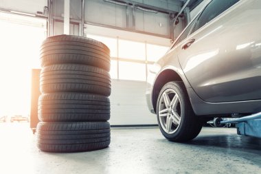 Araba tekerleği tamiri ve iki oto asansör arka görüşü. Atölyede mevsimlik lastik değişimi. Araç lastiği tamiri, denetim onarımı. Arıza sonrası yedek parçaların değiştirilmesi için otomotiv garajı.