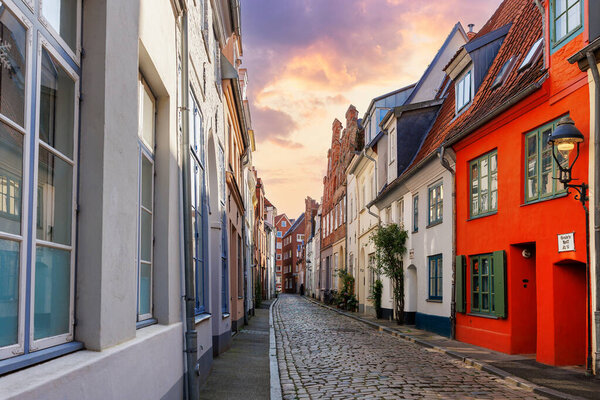 Scenic view old narrow european german Lubeck town street  red brick ancient houses vintage iron stained glass lamp lantern on wall. Cityscape UNESCO heritage city altstadt Germany travel destination.