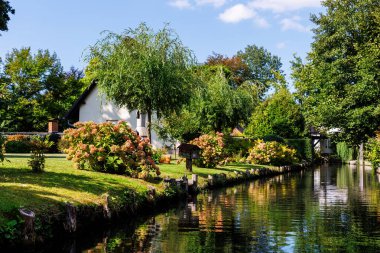 Yeşil nehir kenarındaki bahçe evinin manzarası Alman milli parkı Spreewald yaz güneşli bir günde. Nehir ormanı yeşillik kanal doğa sakin manzara Almanya 'da mavi gökyüzü arka planı.