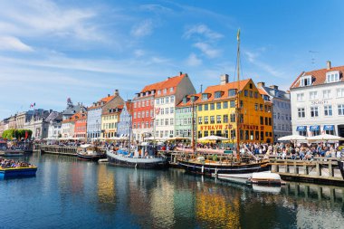 Kopenhag, Danimarka - 20 Mayıs 2023: Güneşli bir günde mavi gökyüzüne karşı Kopenhag Nyhavn limanındaki ünlü renkli ev binası. Avrupa 'nın Danimarka manzarasına demirlemiş tekneler.