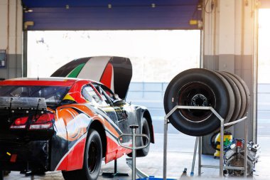 Arkadan Nascar Whelen Euro serisi yarış arabası Motorsport Arena garaj pisti yarış pisti çadırı açık kaputlu hidrolik kaldırıcıya asıldı. Avrupa otomobil sporları yarışması.