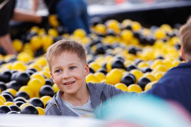 Beyaz saçlı sevimli çocuğun portresi kreşteki oyun odasında ya da çocuk mağazasında top oynarken eğleniyor. Neşeli mutlu çocuk aktivitesi eğlence oyunu.
