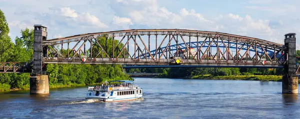 stock image Tourist boat cruises under old historic iron bridge on Elbe River in Magdeburg, Germany with blue sky clouds background landscape. Saxony-Anhalt center cityscape sightseeing water trip.