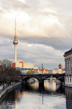 Berlin Mitte, River Spree Bode Müzesi TV Kulesi üzerindeki S-bahn köprüsünü ve merkez bölgedeki tarihi binaları bulutlu bulutlu bir gökyüzü günbatımında görüyor. Alman başkentinin şehir manzarası.