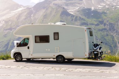 Manzaralı büyük, modern, beyaz aile karavan aracı kaput açık, Avrupa otoyol kenarı, dağlık dağ geçidi, güneşli yaz günü. Karavanın yaşam tarzı macera turizmi.