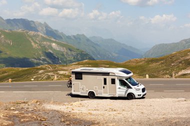 Manzaralı büyük beyaz aile karavan aracı Avrupa otoyolu Alp Dağları 'nı güneşli yaz gününde geçiyor. Karavanın yaşam tarzı macera turizmi Alpler seyahat konsepti.