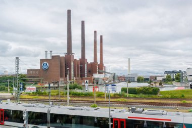 Wolfsburg, Almanya... 18 Ağustos 2024 Wolfsburg şehri Volkswagen fabrikası. VW otomotiv fabrikası Lower Saxony tren istasyonu bulutlu gökyüzüne karşı. Otomatik kriz ekonomik durgunluk.
