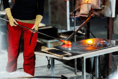 Endüstriyel zanaat atölyesindeki kırılma fırınının içinde erimiş cam şekilli cam boru aleti ile yakın plan cam üfleme. Avrupa 'nın el yapımı üfleme cam tasarımı üretimi.