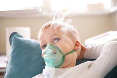 Sevimli küçük çocuk tıbbi nebulizör maskesi takıyor buhar solunum terapisi ciğerleri ve RSV alerji tedavisi soluyor. Portre çocuğu mevsimlik solunum bronşit öksürük ilacı tedavisi görüyor..