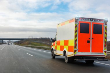 Alman Ambülansı EMS eu uk paramedikler kurtarma minibüsü Avrupa otoyolu banından hızla geçiyor güneşli bir gün yağmuru var. Acil tıbbi yardım aracı. İlk yardım trafik kazası desteği.