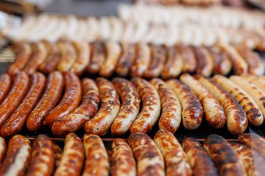 Alman sokak yiyecekleri festivalinde ızgarada pişen sosis ve et bifteklerinin yakın çekimi. Açık büfede ızgara sosis ve ızgara.