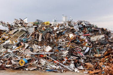 Manzaralı metal hurda yığını, Almanya 'daki endüstriyel fabrika alanına karşı hurdalık geri dönüşüm sahasında paslı metal parçalarının atıldığı büyük bir çöp yığını. Scrapyard atık yönetimi sektörü geçmişi.