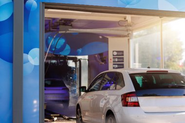 Otomatik otomatik tünel araba yıkama makinesi. Araç kuyruğu araba yıkama istasyonu modern temizlik ekipmanları. Su püskürtüleri ve yansımaları otomotiv bakımı için dinamik bir sahne oluşturur..