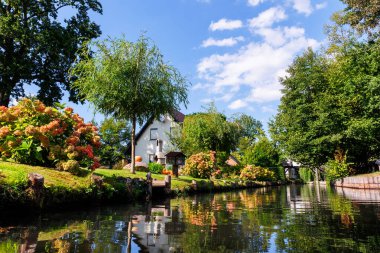 Yeşil nehir kenarındaki bahçe evinin manzarası Alman milli parkı Spreewald yaz güneşli bir günde. Nehir ormanı yeşillik kanal doğa sakin manzara Almanya 'da mavi gökyüzü arka planı.