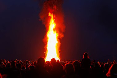 Almanya 'nın alacakaranlık gecesinde toplanan kalabalık geleneksel Paskalya şenlik ateşini kutluyor. Walpurgis gece yangını dışarıda..