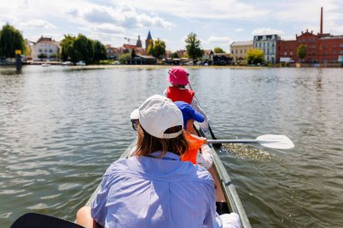 İki çocuk göl suyunda güneşli yaz günlerinde parlak turuncu yeleklerle kano kiralamaktan zevk alıyor. Sağlıklı eğlence aktiviteleri yaşam tarzı tatil seyahati.