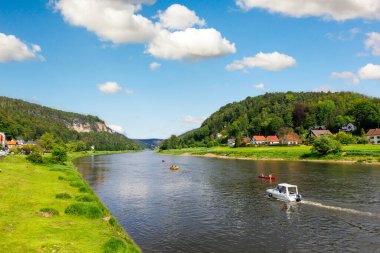 Panoramik manzaralı kiralık tekne Elbe Nehri eğrisinde Sachsische Schweiz Ulusal Parkı Almanya Whelen Koenigstein Dağları 'nda güneşli bir günde yol alıyor. Avrupa doğa gezisi hedefi.