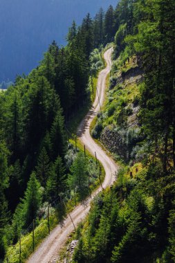 Yılanımsı toprak yol, dramatik dağ yamacındaki sık yeşil ormanların arasından esiyor. Canlı çam ağaçları ve yemyeşil çalılıklar tenha patikalar engin yaz gökyüzü altında huzurlu bir yürüyüş cenneti sunuyor..
