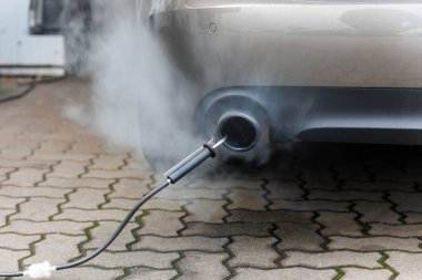 Araba egzoz borusu şehir kaldırımlarındaki emisyon testi sırasında yoğun duman yayar. Kirlilik kontrol cihazı zararlı gazları ölçer. Servis araba merkezi garaj atölyesi. Otomobil onarım denetimi tanısı.