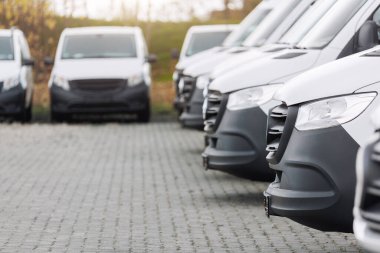 Yeni modern elektrikli hidrojen ya da dizel beyaz minibüsler açık havada park halinde. Kargo şilebi endüstriyel kurye ulaşım lojistik servisi. Ticari araç bakım sigortası.