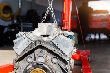 Motorsport Pit 'in garaj kapısı asılmış V8 motor askıya alınmış vinç kaldırma kancası. Yarış garajı atölyesi yarış arabası motor tamiri. Otomatik servis bakım spor ekipmanları.
