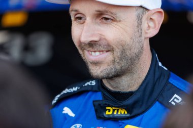 Oschersleben, Almanya. 27 Nisan 2025. Rene Rast, profesyonel yarış arabası sürücüsü, motorsporu sırasında DTM yarış kıyafeti içinde gülümsüyor. Schubert BMW takım logolarıyla yakın plan portresi.