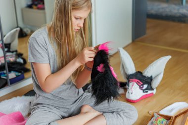 Sevimli sarışın kız yerde oturup pembe siyah kürk kostüm dikiyor. Çocuk ev yapımı tüylü ejderha maskesi yapıyor. Quadrobic Therian fandom alt kültürü. Tasarım hobisi yaratıcı sanat eserleri.