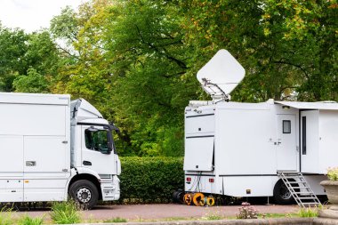 Birçok modern beyaz mobil dijital televizyon yayın kamyonları uydu antenleri online flaş haber kanalı City Park 'ta canlı yayınlanıyor. İnternet iletişim medyası ağ donanımı.