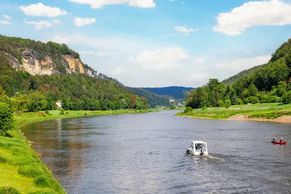 Panoramik manzaralı kiralık tekne Elbe Nehri eğrisinde Sachsische Schweiz Ulusal Parkı Almanya Koenigstein Whelen Dağları 'nda güneşli bir günde yol alıyor. Avrupa doğa gezisi hedefi.
