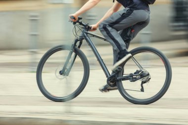 Spor takım elbiseli bir adam, güneşli bir günde Avrupa sokaklarının dinamik hareketlerinde hızlı siyah bisiklet sürüyor. Şehir bisikleti işe gidiş-dönüş. Çalışan sağlıklı yaşam tarzı çevre dostu ulaşım..