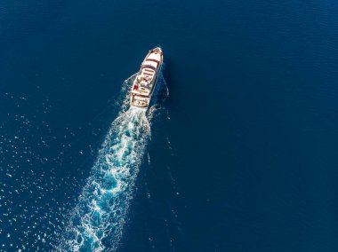 Hava aracı manzaralı lüks bir yat turkuaz mavi deniz suyuyla güneşli yaz gününde Akdeniz manzarası arka planında seyrediyor. Motorlu tekne kiralama kiralama sigortası..