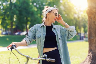 Portre genç, yetişkin, güzel bir kadın. Kırmızı antika bisikleti ve yeşil şehir parkı parlak güneşli yaz günü giysisi. Dışarıda bisiklete binen mutlu, güzel bir kadın. Sağlıklı yaşam tarzı.